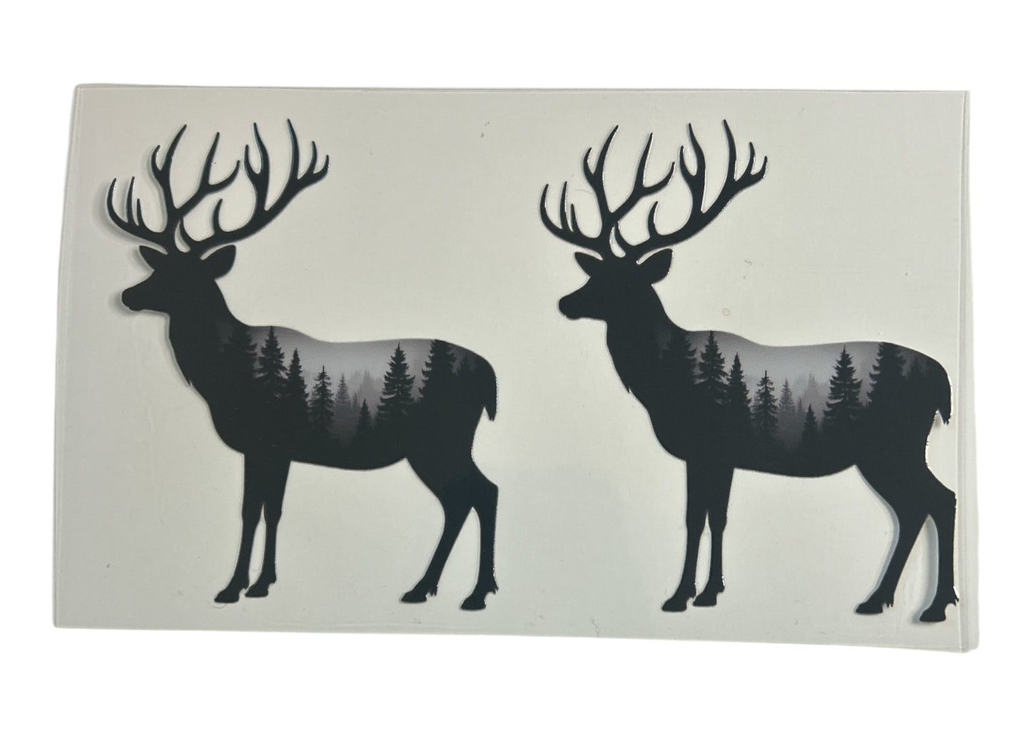 Two black deer silhouettes with forest design on a white background