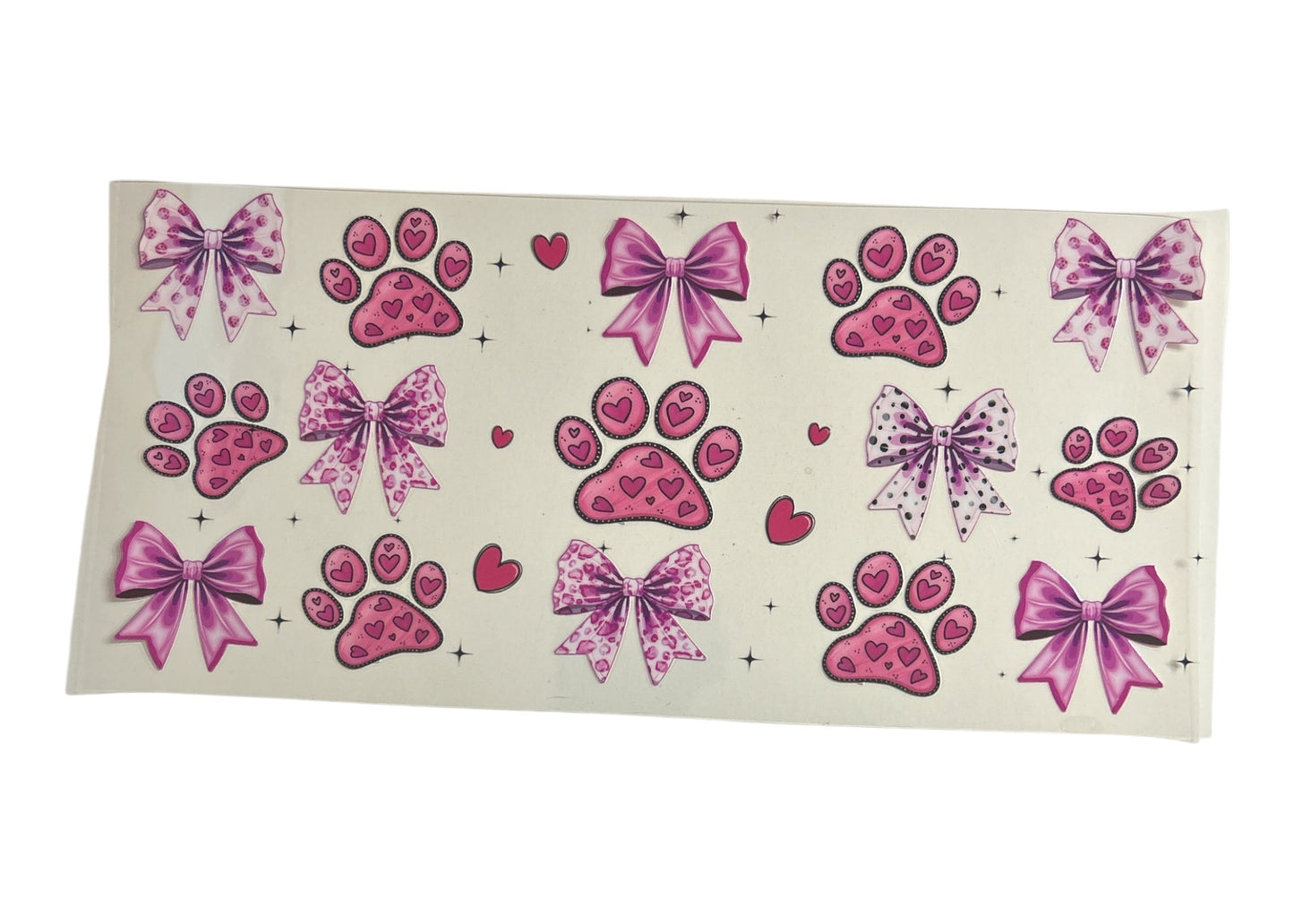 Sheet of pink paw print and bow designs on a clear background