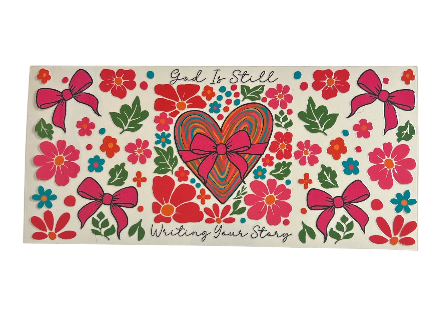 Decorative cup wrap with heart, flowers, and 'God Is Still Writing Your Story' text on a clear background