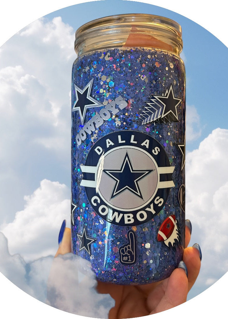 Dallas Cowboys-themed glittery tumbler held against a cloudy sky background