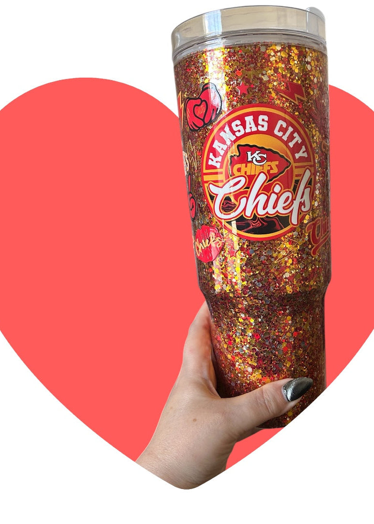 Tumbler with Kansas City Chiefs logo held by a hand against a red heart background