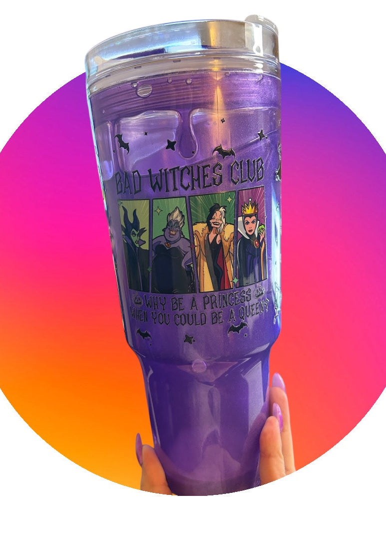 Purple tumbler with 'Bad Witches Club' design held against a colorful gradient background