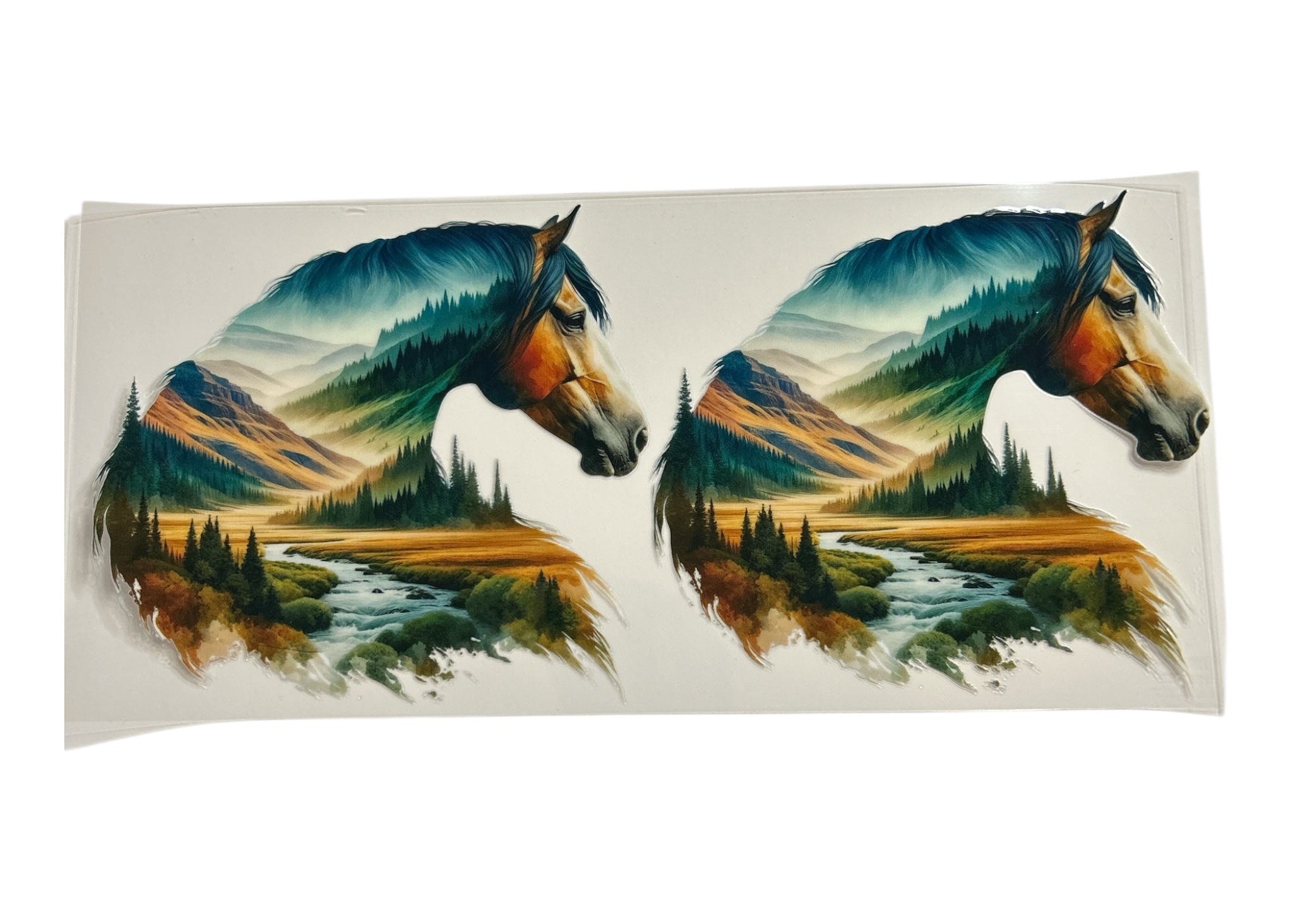 Two horse heads with mountain and forest scenery inside on a clear background