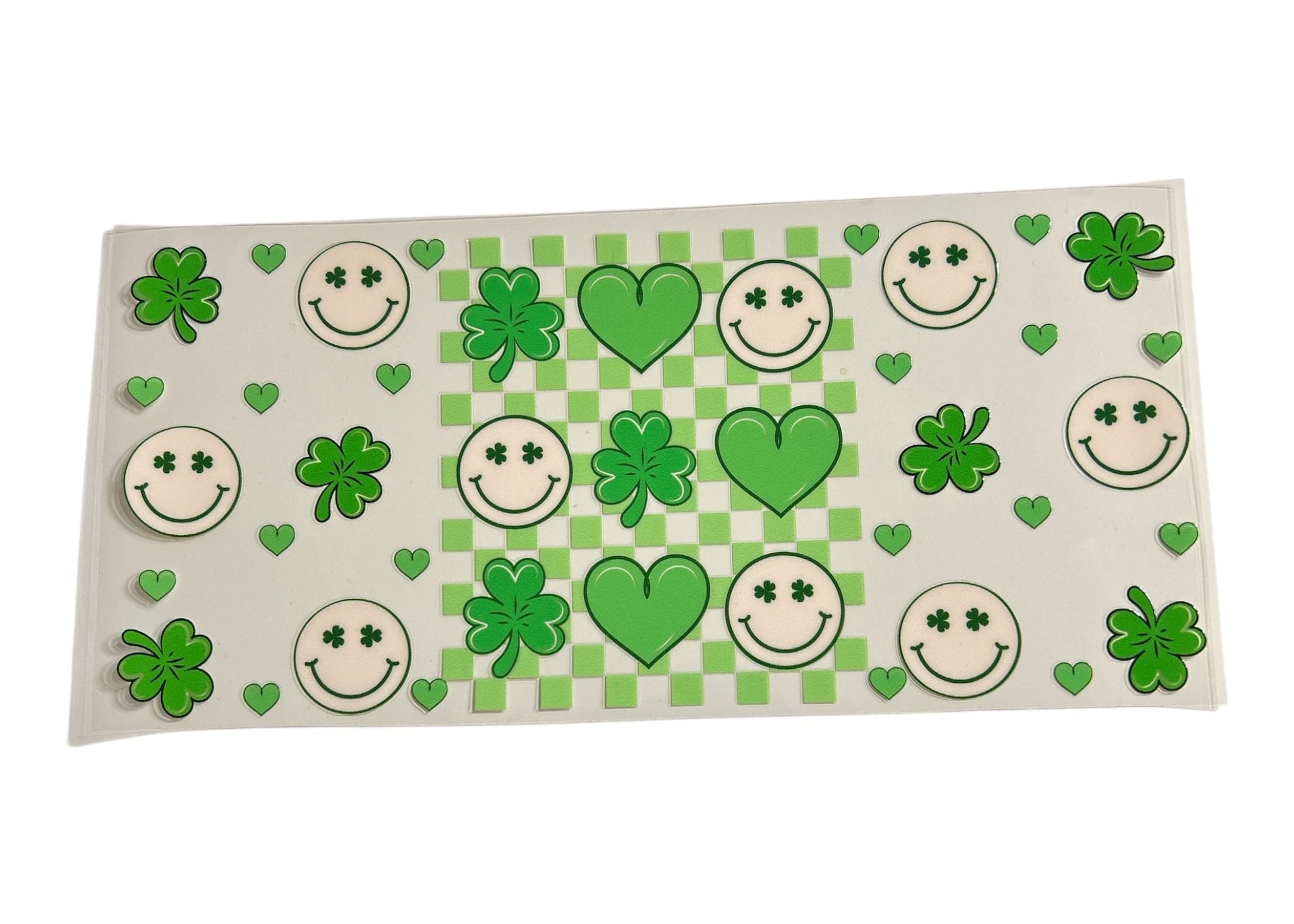 Decorative cup wrap with green shamrocks, hearts, and smiley faces on a checkered background