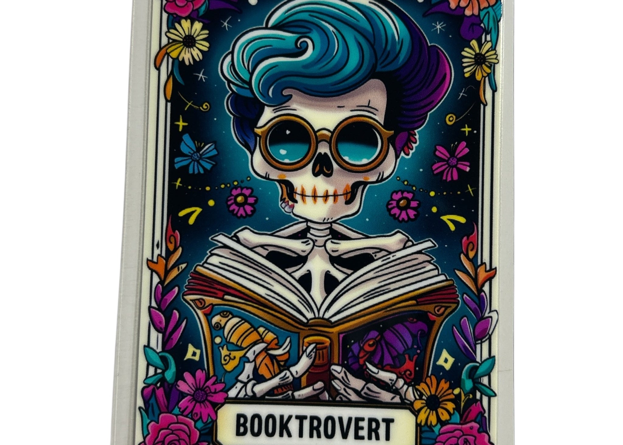 Colorful decal with a skeleton reading an open book, surrounded by flowers and decorative elements, with 'Booktrovert' branding.