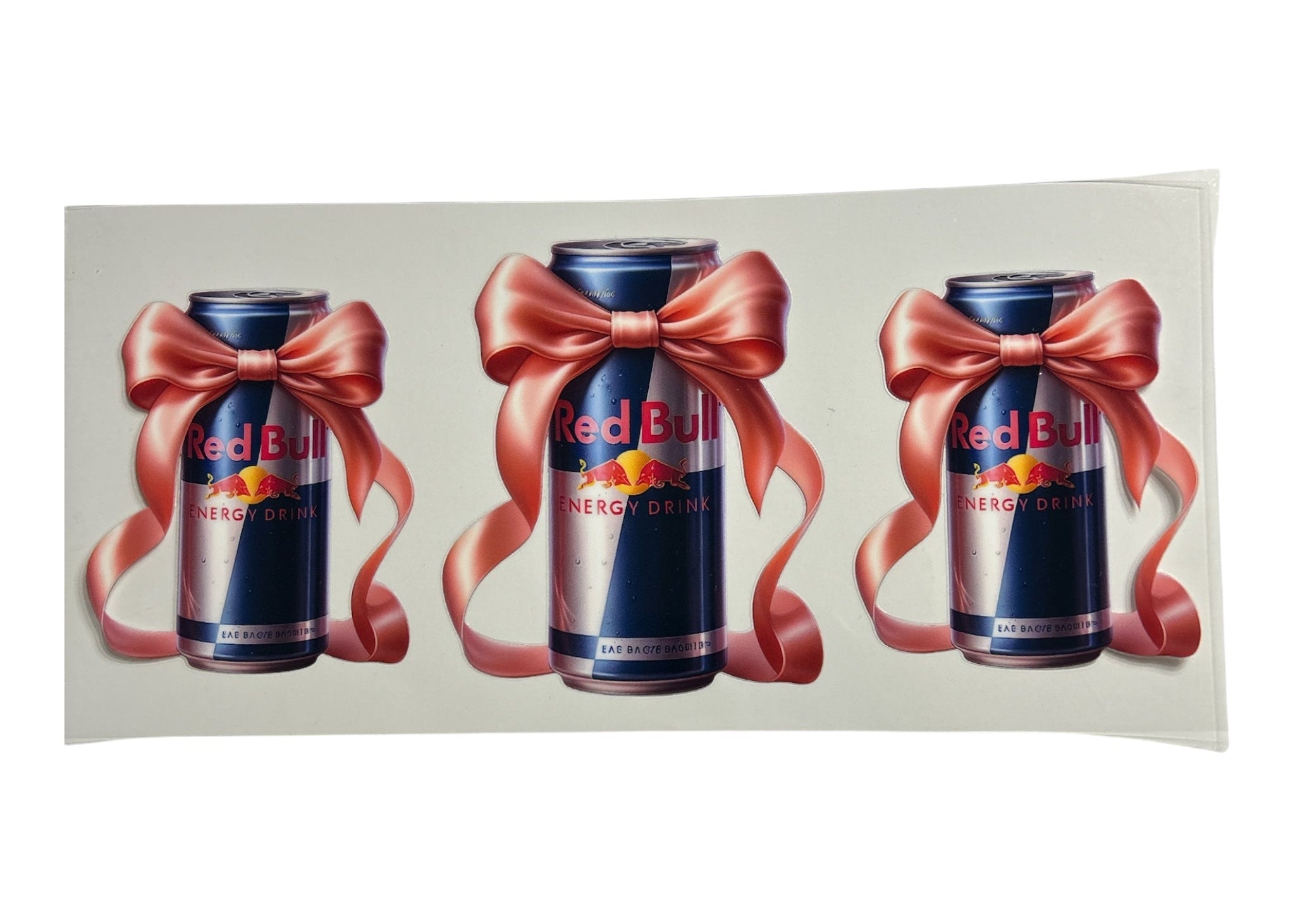 Three Red Bull energy drink cans with pink bows on a white background