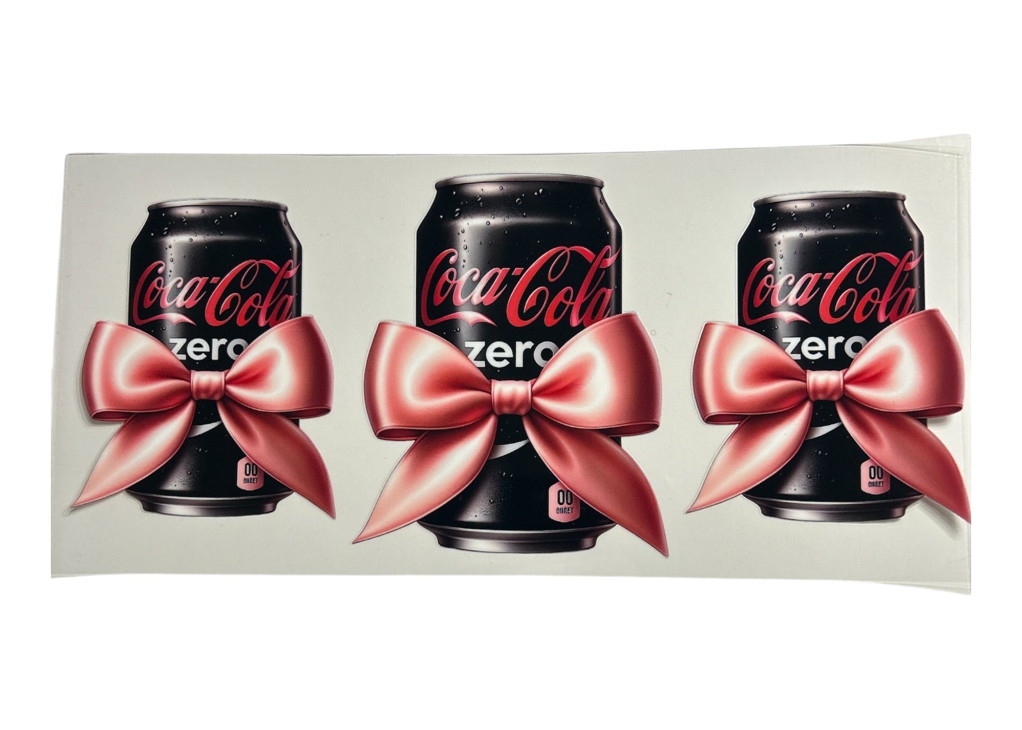 Three Coca-Cola Zero cans with pink bows on a white background