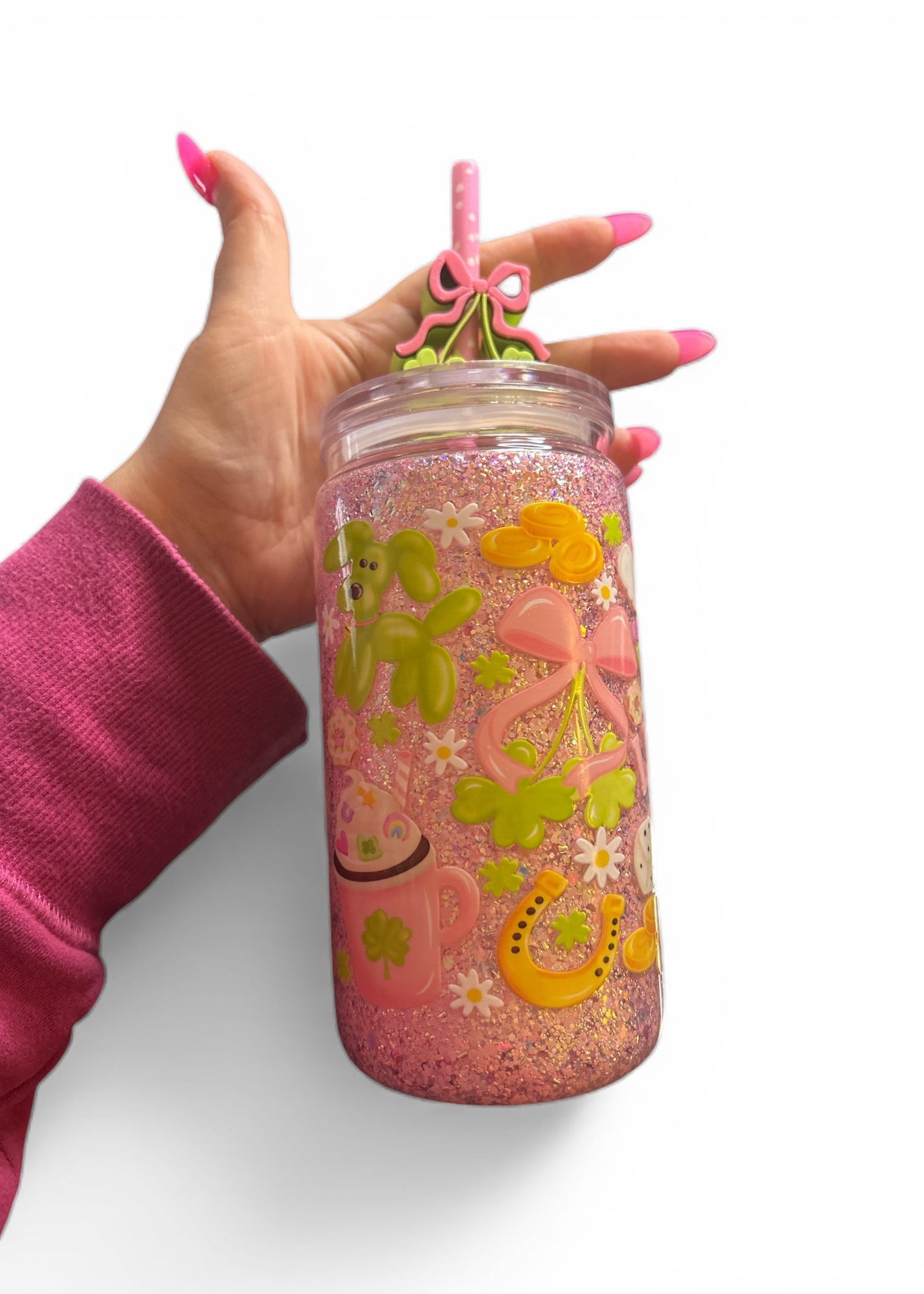 Hand holding a pink glittery tumbler with floral designs on a white background