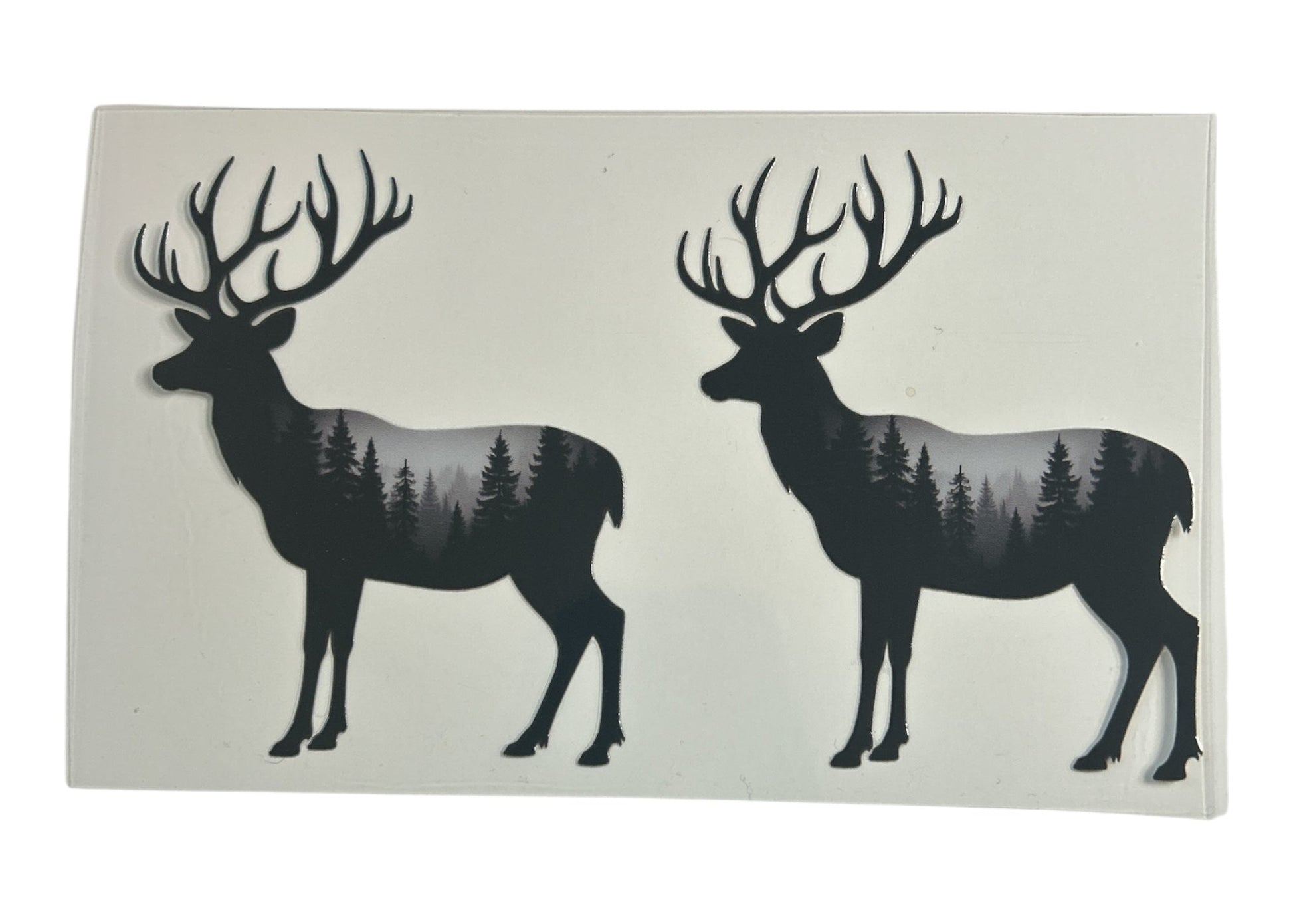 Two black deer silhouettes with forest design on a white background