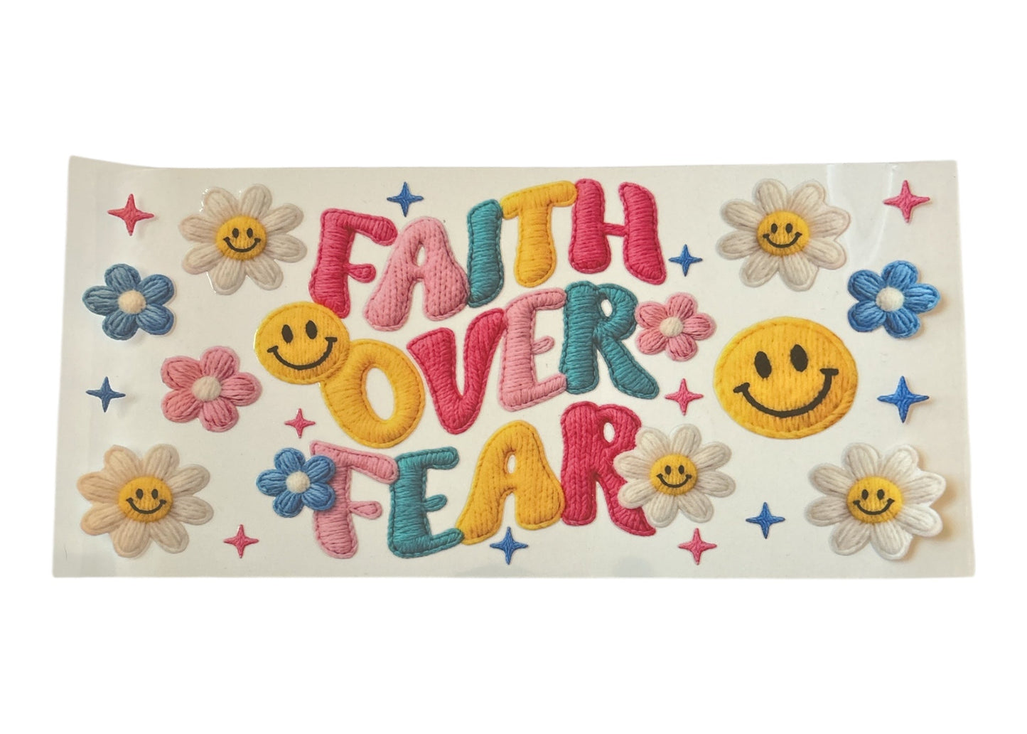 Embroidered-look cup wrap with 'Faith Over Fear' text and smiley faces on a white background