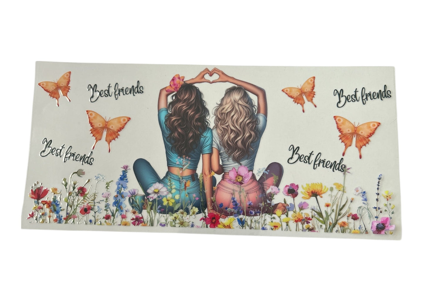 Decorative cup wrap with two women sitting on grass, surrounded by flowers and butterflies, with 'Best friends' text.