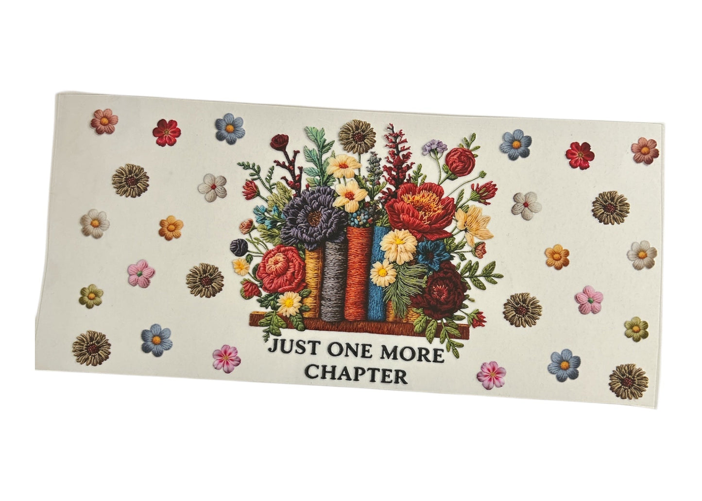 Custom cup wrap design with a realistic embroidered texture showing books as flower vases with a lush bouquet, accompanied by the text "JUST ONE MORE CHAPTER" and scattered small blossoms.