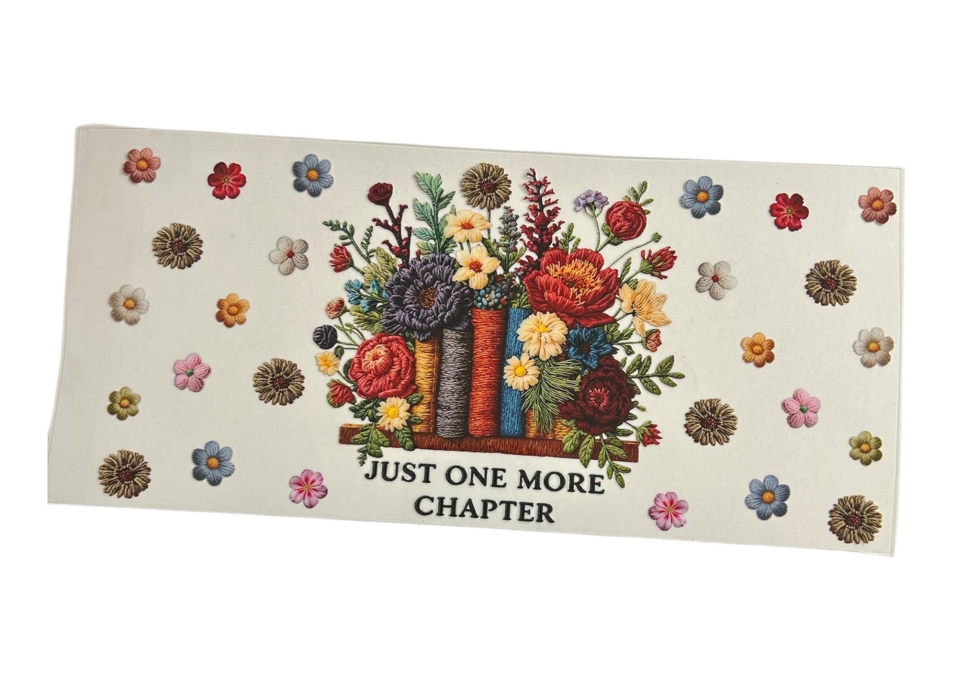Custom cup wrap design with a realistic embroidered texture showing books as flower vases with a lush bouquet, accompanied by the text "JUST ONE MORE CHAPTER" and scattered small blossoms.