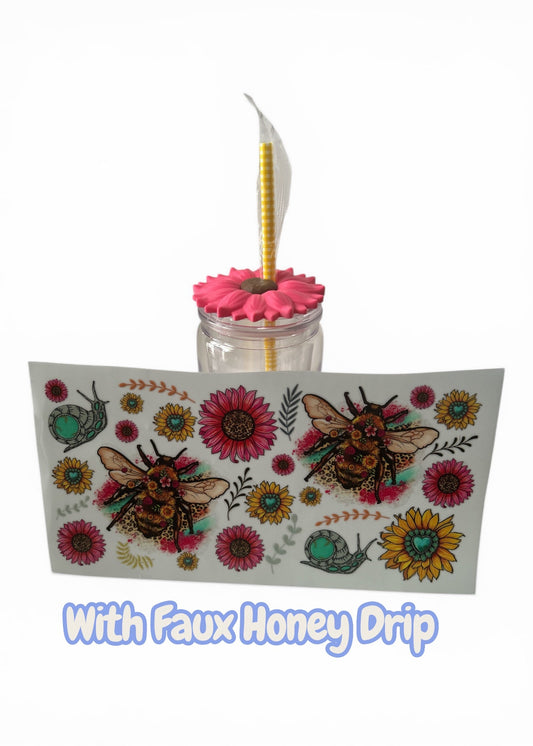 Decorative glass with pink flower and yellow straw, featuring bee and floral design on a white background.